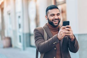 Smiling man with smart phone outdoors in the city