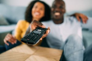 Cute young couple cuddling while watching tv.