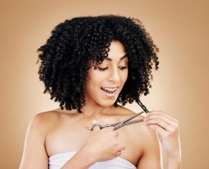Woman, hair and cut for change, transformation and style with happiness, smile or brown studio background. Scissors, self care or freedom from loss, beauty and hairdresser for curls, positive or face